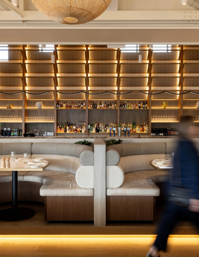 Dining room at First Mates, Last Laugh with curved banquette seating, illuminated timber shelving and coastal-inspired interiors