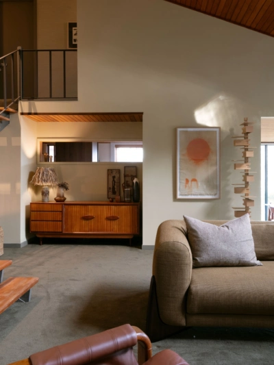 1970s-inspired living room featuring warm neutral walls painted in Aalto Compatible, timber ceilings and vintage-inspired furniture.