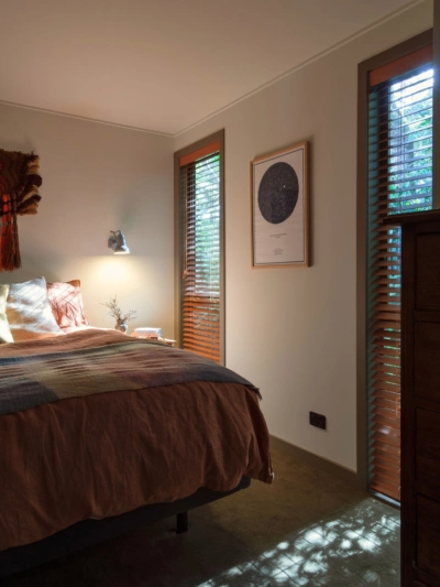 1970s-inspired bedroom featuring warm neutral walls painted in Aalto Endless, timber window shutters and earthy-toned bedding.