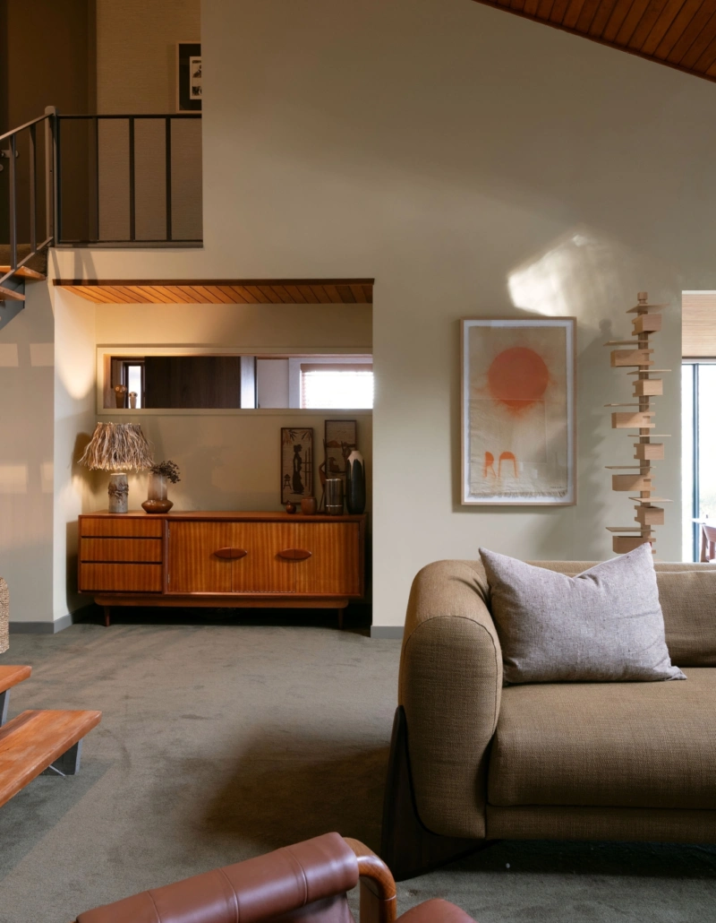 1970s-inspired living room featuring warm neutral walls painted in Aalto Compatible, timber ceilings and vintage-inspired furniture.